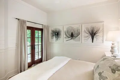 a white bedroom with a bed and a window at Hammock Cottage in Rosemary Beach