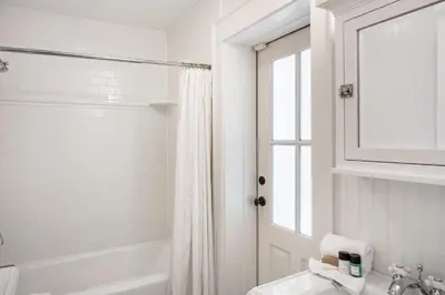 a white bathroom with a tub and a sink at Hammock Cottage in Rosemary Beach