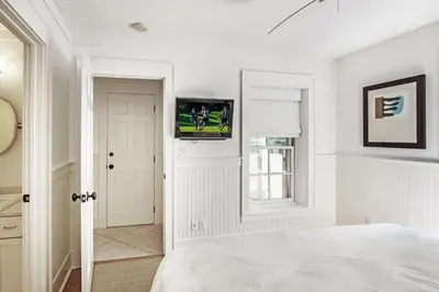 a bedroom with a bed and a television on a wall at Hammock Cottage in Rosemary Beach