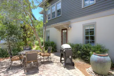 a patio with a grill and chairs in front of a house at Hammock Cottage in Rosemary Beach