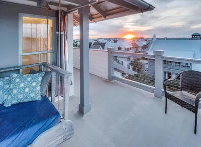 a bed on a balcony with the sunset in the background at Thyme & Place in Rosemary Beach