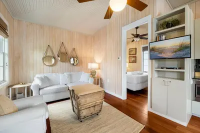 a living room with a white couch and a tv at Uncorked Carriage House in Rosemary Beach