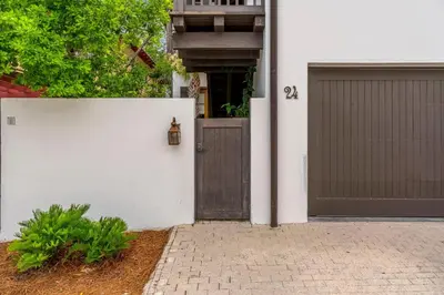 a white house with a gate and a garage at Uncorked Carriage House in Rosemary Beach