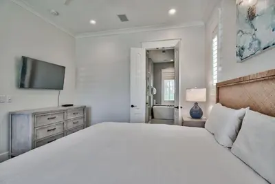 a white bedroom with a bed and a television at Southern Serenity Cottage in Rosemary Beach