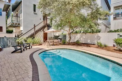 a swimming pool with a table and chairs next to a building at Southern Serenity Cottage in Rosemary Beach