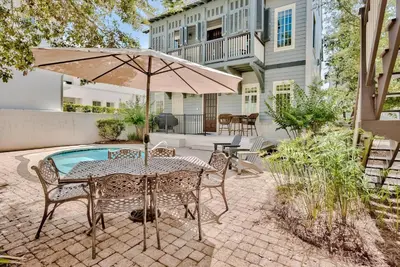 a patio with a table with an umbrella and chairs at Southern Serenity Cottage in Rosemary Beach