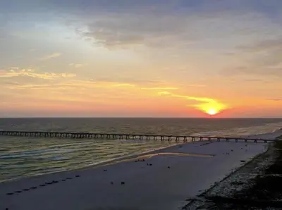 a pier stretches out into the ocean at sunset at Beachfront Bliss Awaits: 2-Bed, 2-Bath Condo at Sterling Reef - Sleeps 6! in Panama City Beach
