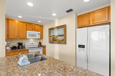 a kitchen with a sink and a refrigerator at Beachfront Bliss Awaits: 2-Bed, 2-Bath Condo at Sterling Reef - Sleeps 6! in Panama City Beach