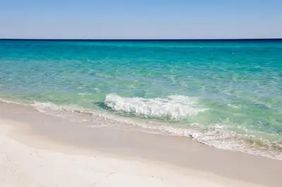 a wave breaking on a beach near the ocean at Sugar Sand Retreat – 3-Bed, 2-Bath Beach Getaway with Private Pool, Sleeps 8! in Santa Rosa Beach