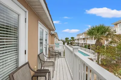 a balcony of a condo with chairs and a pool at Escape to Sand Dollar Holler: Coastal Retreat, 3 Beds, 25 Baths, Sleeps 10! in Panama City Beach
