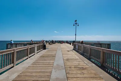 a pier with people walking on it next to the water at Shores of Panama 1217 | Emerald Beach Retreat in Panama City Beach