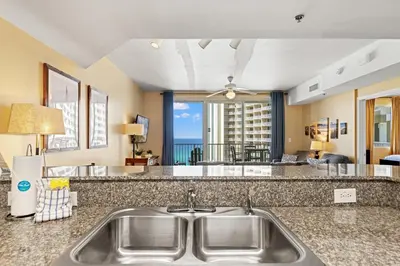 a kitchen sink with a view of a living room at Shores of Panama 1217 | Emerald Beach Retreat in Panama City Beach