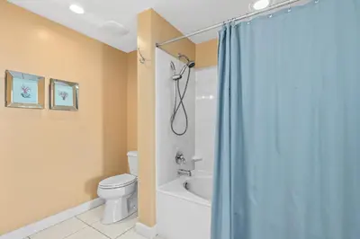 a bathroom with a blue shower curtain and a toilet at Anchor's Way! Come Visit Our Beautiful 2 BR, 2BA Oceanfront Retreat! Sleeps 6! in Panama City Beach
