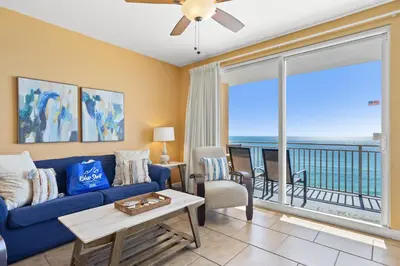a living room with a blue couch and a balcony at Anchor's Way! Come Visit Our Beautiful 2 BR, 2BA Oceanfront Retreat! Sleeps 6! in Panama City Beach