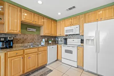 a kitchen with wooden cabinets and white appliances at Anchor's Way! Come Visit Our Beautiful 2 BR, 2BA Oceanfront Retreat! Sleeps 6! in Panama City Beach