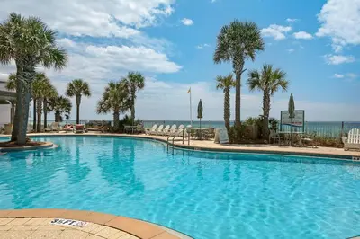 a large swimming pool with palm trees and the ocean at Aqua Resort 706 in Panama City Beach