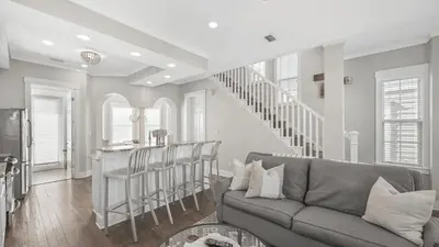 a living room with a couch and a staircase at 30A Emerald Waters by AvantStay Pool Bikes Bonfires in Panama City Beach
