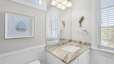 a white bathroom with a sink and a mirror at 30A Emerald Waters by AvantStay Pool Bikes Bonfires in Panama City Beach