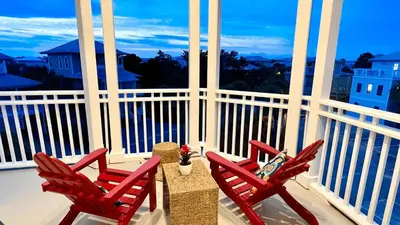 two red chairs and a table on a balcony at 30A Emerald Waters by AvantStay Pool Bikes Bonfires in Panama City Beach