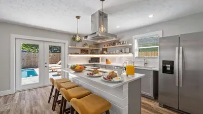a kitchen with a large island with bar chairs at Walk to Beach Golf Cart Bikes Pool Fire Pit Bonfires G By The Sea by AvantStay in Panama City Beach