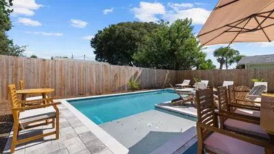 a swimming pool with chairs and an umbrella at Walk to Beach Golf Cart Bikes Pool Fire Pit Bonfires G By The Sea by AvantStay in Panama City Beach