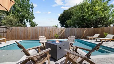 a patio with chairs and a grill next to a swimming pool at Walk to Beach Golf Cart Bikes Pool Fire Pit Bonfires G By The Sea by AvantStay in Panama City Beach