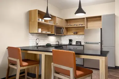 a kitchen with a black counter top and wooden cabinets at Candlewood Suites Panama City - Tyndall AFB by IHG in Panama City