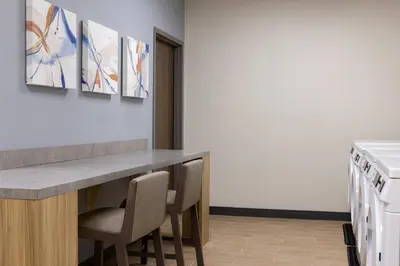 a kitchen with a counter with chairs and paintings on the wall at Candlewood Suites Panama City - Tyndall AFB by IHG in Panama City