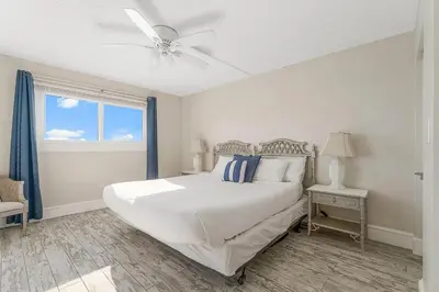 a white bedroom with a bed and a ceiling fan at Regency Towers 1212 by Emerald Coast Retreats in Panama City Beach