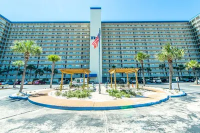a large building with palm trees in front of it at Regency Towers 1212 by Emerald Coast Retreats in Panama City Beach