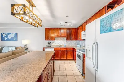 a kitchen with wooden cabinets and a refrigerator at Laketown Wharf #1219 by Nautical Properties in Panama City Beach