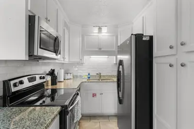 a kitchen with a stainless steel refrigerator and white cabinets at Summit #1105 by Nautical Properties Vacation Rentals in Panama City Beach