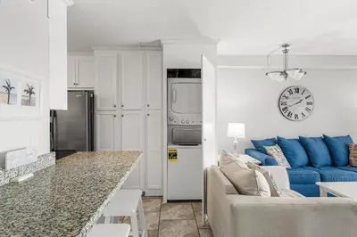 a living room with a couch and a clock on the wall at Summit #1105 by Nautical Properties Vacation Rentals in Panama City Beach