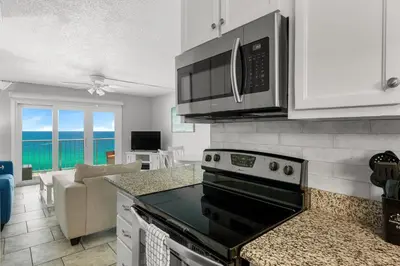 a kitchen with a stove top oven next to a living room at Summit #1105 by Nautical Properties Vacation Rentals in Panama City Beach