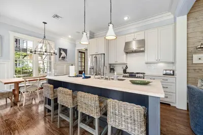 a kitchen with white cabinets and a large island with chairs at 67 Wiggle Lane - Rosemary Beach - Steps to Tennis Courts, Beach, Pools! in Rosemary Beach