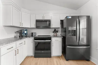 a kitchen with white cabinets and a stainless steel refrigerator at Casa de Tortugas - a spacious townhome with 30a private beach access in Seacrest