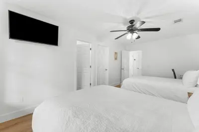 a white bedroom with two beds and a ceiling fan at Casa de Tortugas - a spacious townhome with 30a private beach access in Seacrest