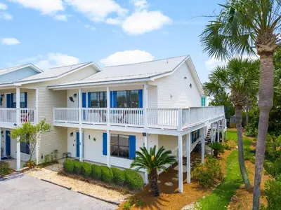 a white house with palm trees in front of it at Casa de Tortugas - a spacious townhome with 30a private beach access in Seacrest