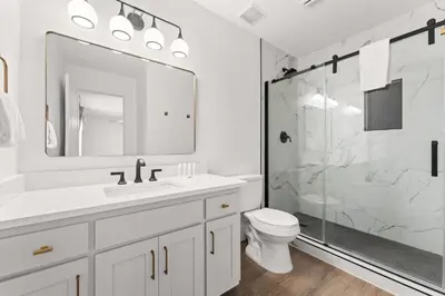 a white bathroom with a shower and a toilet at Casa de Tortugas - a spacious townhome with 30a private beach access in Seacrest