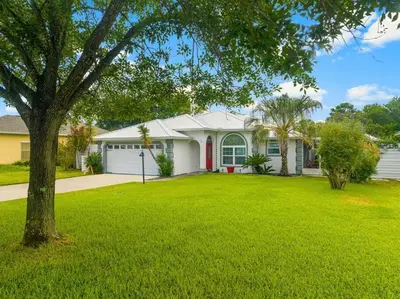 a white house with a tree in a yard at Making Memories in Panama City Beach