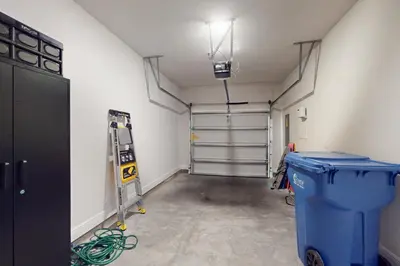 a garage with a blue trash can and a garage door at Steps to Sand and Surf! Family-Friendly PCB Retreat in Panama City Beach