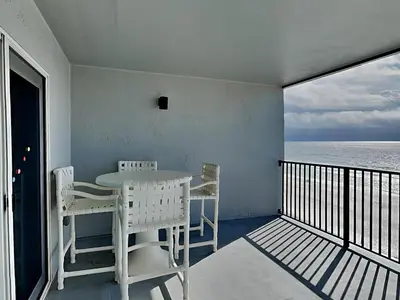 a balcony with a table and chairs and the ocean at Mariner East #602 in Panama City Beach