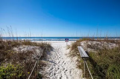 a bench sitting on a sandy beach near the ocean at Mariner East #602 in Panama City Beach