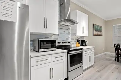 a kitchen with white cabinets and a stainless steel refrigerator at Spacious 4-Bed, 3-Bath Beach House – Sleeps 12 for the Perfect Getaway in Panama City Beach