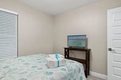a bedroom with a bed and a television on a table at Spacious 4-Bed, 3-Bath Beach House – Sleeps 12 for the Perfect Getaway in Panama City Beach