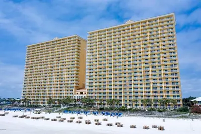 a large yellow building with chairs and a beach at Calypso 203 1 Bedroom Gulf Front in Panama City Beach