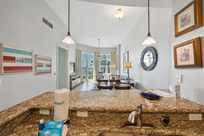 a kitchen with a counter top and a living room at Aqua 110 New Remodel Ground Level, The most Requested Unit in Building in Panama City Beach