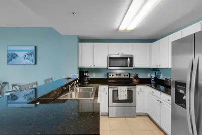a kitchen with white cabinets and stainless steel appliances at 2007 Calypso East 1 Bedroom in Panama City Beach