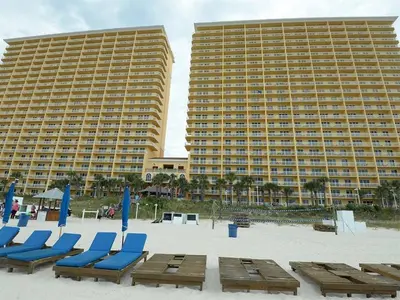 two large buildings with blue chairs and chairs on the beach at 2007 Calypso East 1 Bedroom in Panama City Beach
