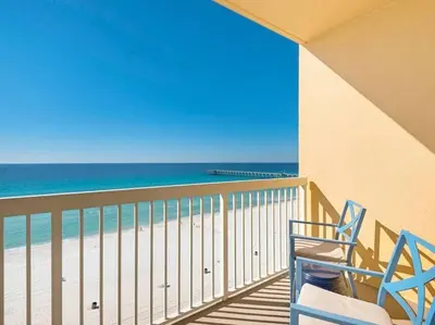 a balcony with a blue chair and the beach at 2007 Calypso East 1 Bedroom in Panama City Beach